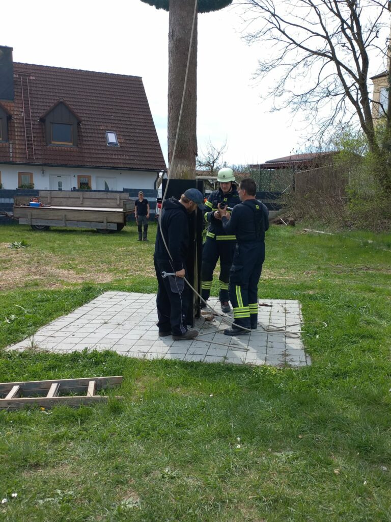 Feuerwehrleute stellen Maibaum auf.