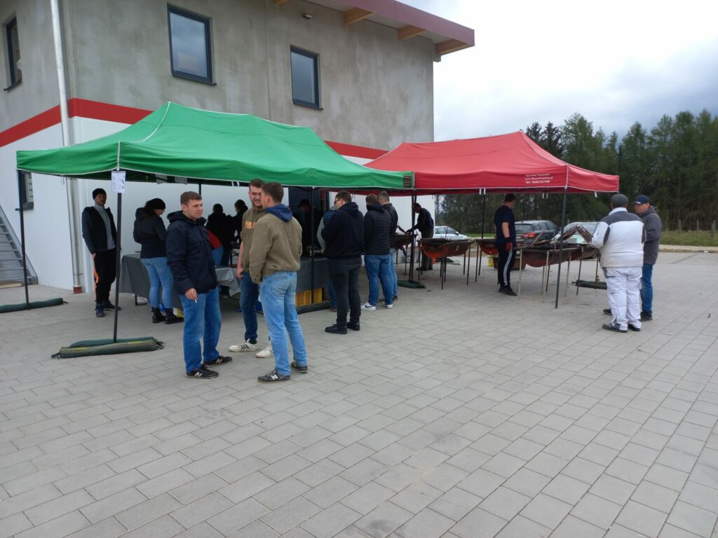 Personen unter grünem und rotem Zelt bei Veranstaltung.