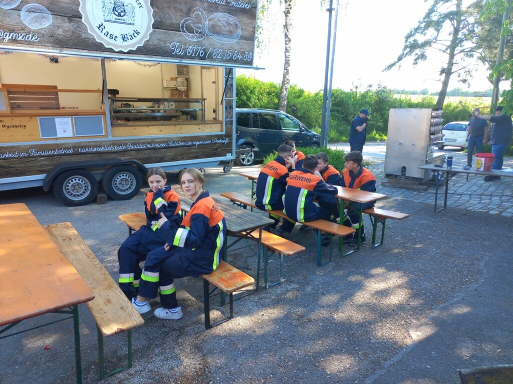 Jugendfeuerwehr in Uniformen sitzt auf Bänken.