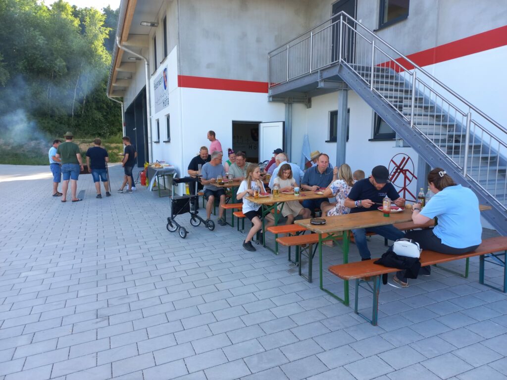 Menschen essen zusammen im Freien vor Gebäude.